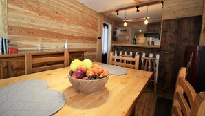 A wooden interior with a dining table, chairs, and a fruit bowl. - Baus's Cabins. A mountain cabin in the village—warm, cozy, and offering breathtaking views. (Turin)