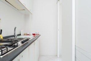 Une cuisine moderne équipée d’une cuisinière à gaz, de meubles blancs et d’un évier en acier inoxydable.