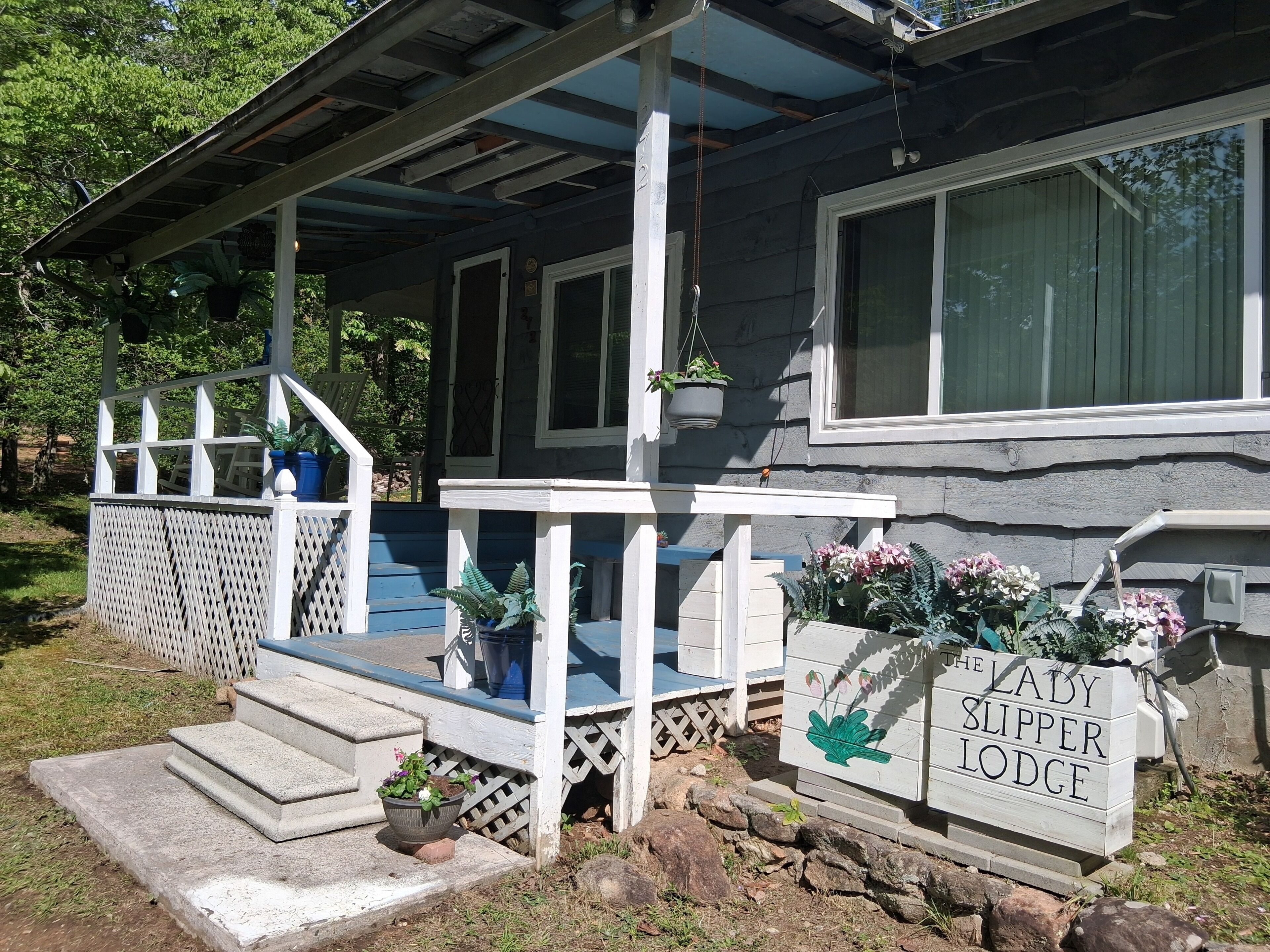 Uma casa com varanda, degraus e uma placa com a inscrição 'The Lady Slipper Lodge'.