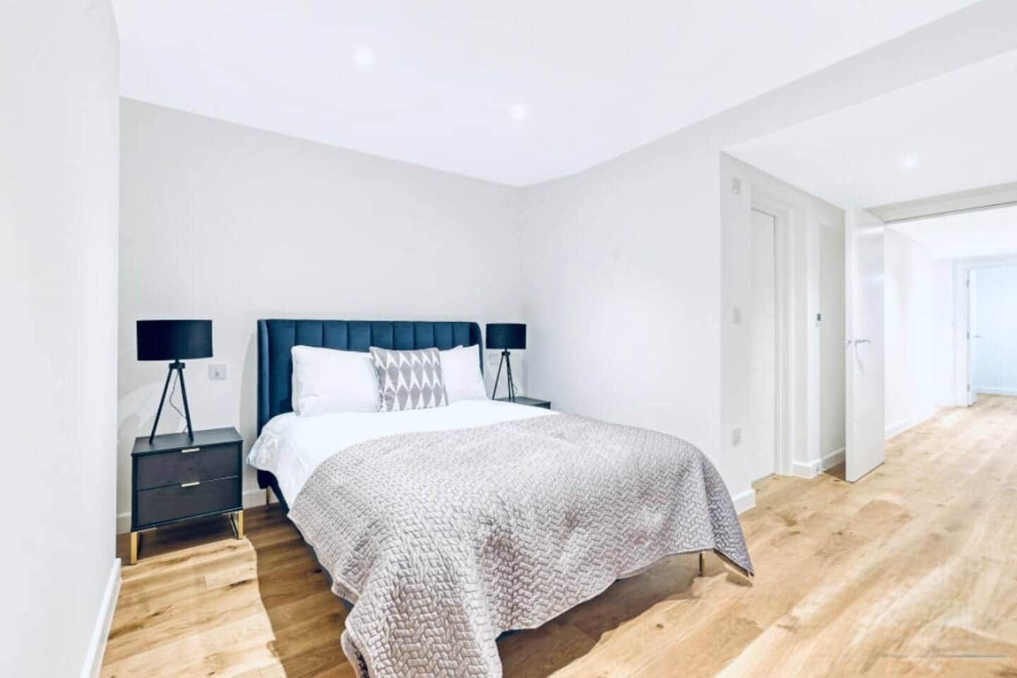 Un dormitorio moderno con cama, dos mesitas de noche y un ventanal grande.
