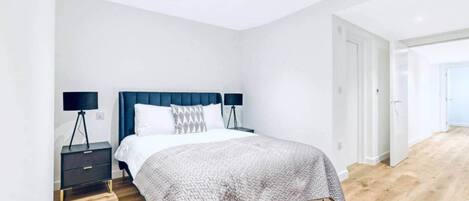 Un dormitorio moderno con cama, dos mesitas de noche y un ventanal grande.
