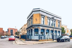 A corner building with a blue facade, numbered 'No 86,' and a black car parked in front. - Detached Family Home with Free Parking (London)