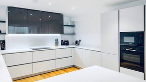 Eine moderne Küche mit weißen Schränken, einem eingebauten Backofen und einer Bosch-Mikrowelle.