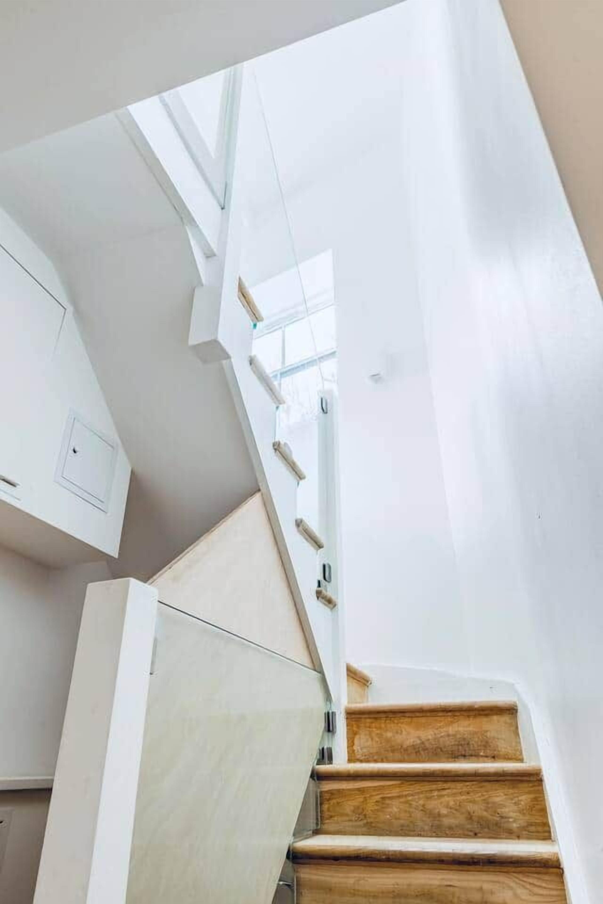 A modern interior with a wooden staircase leading to a landing.