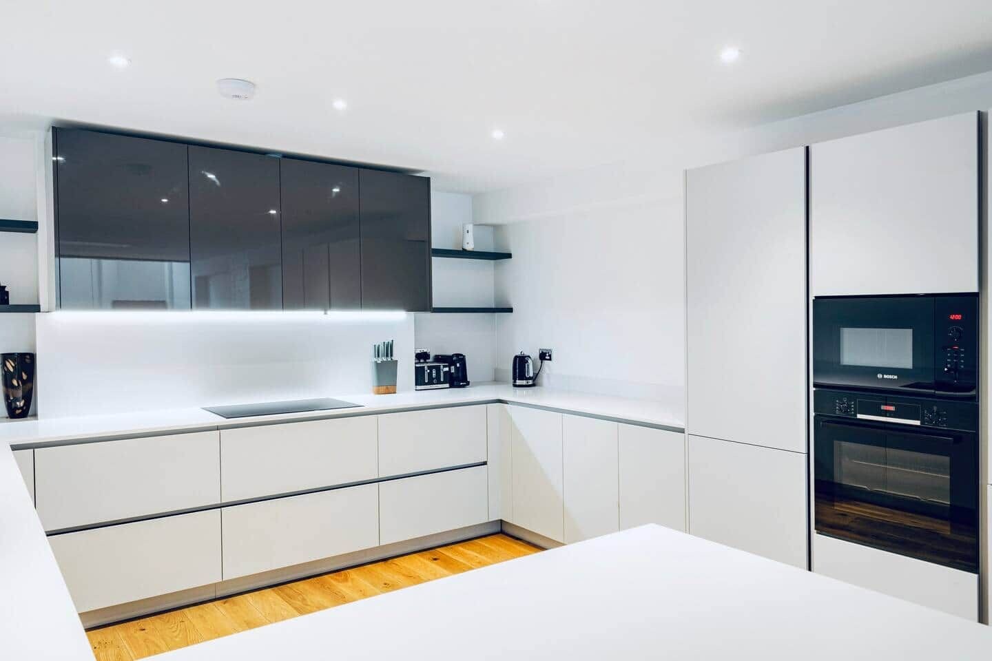 A modern kitchen with white cabinetry, a built-in oven, and a Bosch microwave.