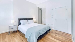 Ein modernes Schlafzimmer mit einem Bett, Nachttischen und einem Kleiderschrank.