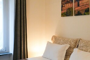 Een hotelkamer met een bed, een raam met gordijnen en een muur met twee ingelijste foto's.