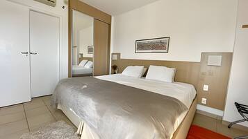 Habitación de hotel con una cama grande, un armario, un espejo y un cuadro en la pared.