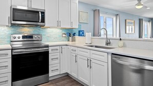 Una cocina moderna con armarios blancos, electrodomésticos de acero inoxidable y un salpicadero azul.