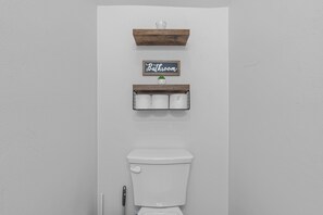 Ein Badezimmer mit Toilette, zwei Holzböden und einem Schild mit der Aufschrift 'Bathroom'.