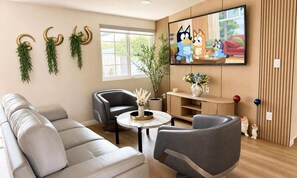 Ein modernes Wohnzimmer mit einer Couch, zwei Sesseln, einem Couchtisch, einem Fernseher und dekorativen Wandelementen.