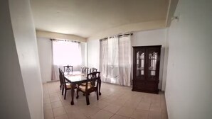 Ein Essbereich mit Tisch und Stühlen, eine Tür mit Fenster und ein Fliesenboden.