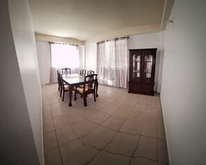 A dining area with a table and chairs, a door with a window, and a tiled floor. - Montes Vacation Home (Palo Seco)