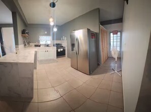 A kitchen with a marble countertop, stainless steel appliances, and a tiled floor. - Montes Vacation Home (Palo Seco)