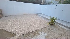 Eine Terrasse mit Kiesboden, einer Holzbank und einem Blumentopf.