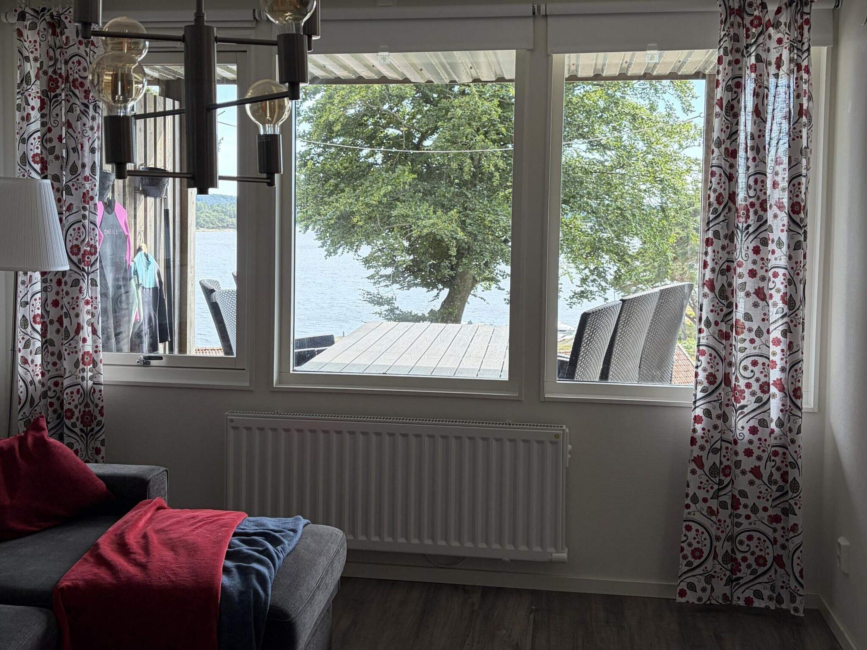 A room with a view of a lake, a sofa with a red blanket, and a radiator.
