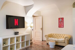 A room with a television, a door, a poster, a sofa, and a small table. - Torino | Il Vicolo Apartment (Torino)