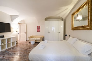 Ein Hotelzimmer mit einem großen Bett, einem Fernseher, einem Kleiderschrank und einem Spiegel.