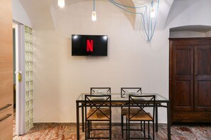 Ein Essbereich mit Tisch und Stühlen, einem an der Wand montierten Fernseher und einer Holzkommode.