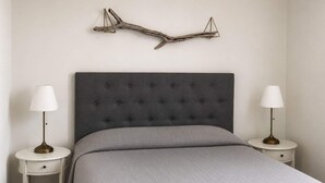 A bedroom with a tufted headboard, a grey quilted bedspread, two bedside tables with lamps, and a wall-mounted branch decoration. - 5 Star Holiday Home in Uddevalla (Uddevalla)