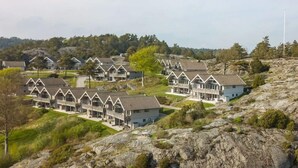 A cluster of modern, multi-story buildings with a uniform architectural style, situated on a rocky hillside with a backdrop of trees and a clear sky. - 5 Star Holiday Home in Uddevalla (Uddevalla)