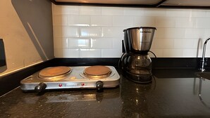 Cocina con dos estufas eléctricas, una cafetera y un salpicadero de azulejos.