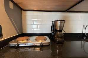 Cocina con dos estufas eléctricas, una cafetera y un salpicadero de azulejos.