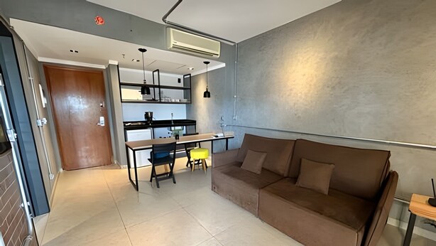 Una sala de estar moderna con un sofá, una mesa de comedor con sillas y una cocina con refrigerador y fregadero.