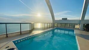 Una piscina interior con vistas al mar y un edificio moderno al fondo.