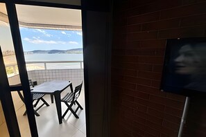 Un balcón con una mesa y sillas, vista al mar y una pared de ladrillo.