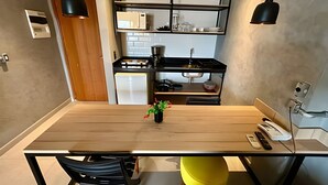Una cocina moderna con una mesa de comedor de madera, lámparas colgantes negras y una pequeña planta.