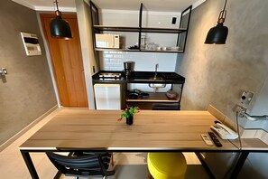 Ett modernt kök med ett matbord i trä, svarta hänglampor och en liten växt.