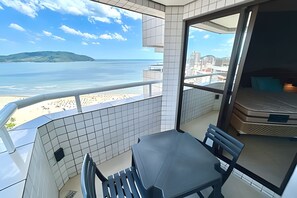 A balcony with a view of the beach and ocean, a table, chairs, and a mattress. - SHB Desfrute do Conforto à Beira-Mar (Santos)