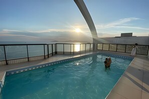 Una piscina con vista al mar y al atardecer.