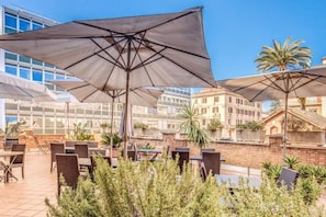 An outdoor patio with tables and chairs, large umbrellas, and a view of buildings. - Villa Borghese House (Rome)