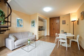 A living room with a sofa, coffee table, and dining area with chairs. There is a kitchen in the background. - Villa Borghese House (Rome)