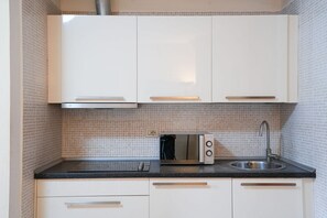 A kitchen with white cabinets, a black countertop, a built-in microwave, and a sink. - Villa Borghese House (Rome)