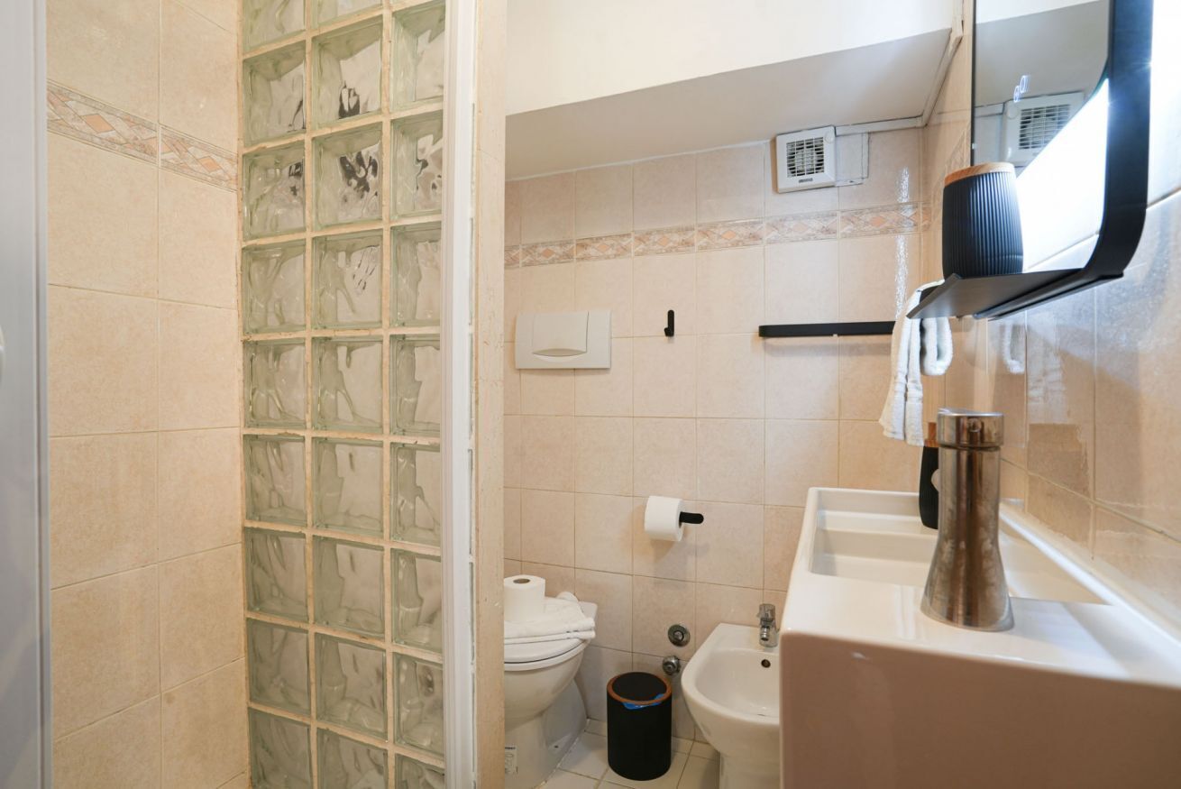 A bathroom with a toilet, bidet, sink, and a glass shower enclosure.