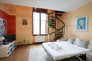 A bedroom with a bed, a TV, a bookshelf, a window, and a spiral staircase. - Villa Borghese House (Rome)