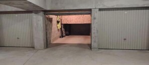 Ein großer, leerer, hallenartiger Raum mit Betonböden und -wänden, zwei geschlossenen Garagentoren und einer an der Wand angelehnten Leiter.