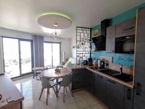 Eine moderne Küche mit Essbereich, großen Fenstern und Blick ins Freie.