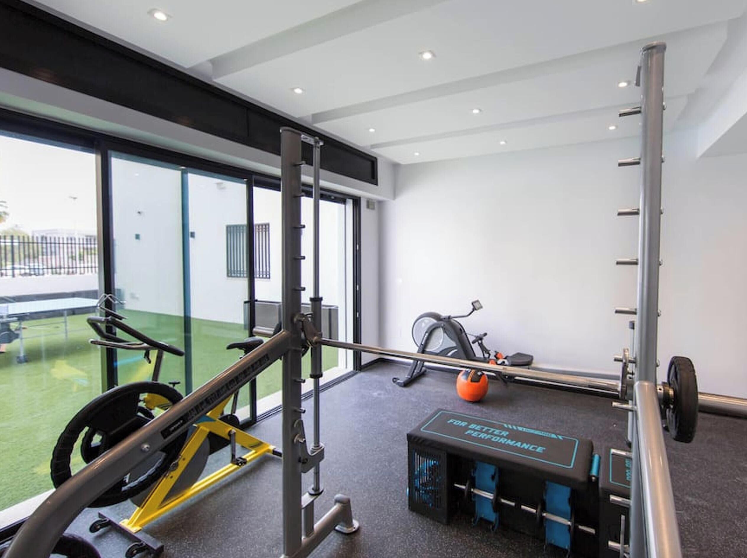 Un gimnasio con una estructura para sentadillas, una banca para pesas y una bicicleta estática.