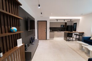 A modern living space with a kitchen, dining area, and a TV mounted on the wall. - Sunset 205 Luxury 1bd with gym (Tunis)