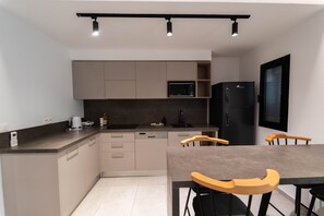 Eine moderne Küche mit eingebauten Geräten, eine Essecke mit Tisch und Stühlen sowie ein schwarzer Kühlschrank.