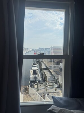 Una habitación con un ventanal que da a un muelle con barcos y vistas de la ciudad.