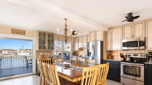 A modern kitchen with a dining area, featuring a large island, stainless steel appliances, and a view to the outside. - Waterfront Lagoon Escape , Sunset Views, Private Dock and Minutes to LBI (Stafford Township)