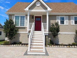 A two-story house with a red front door, white railings, and a small porch. - Waterfront Lagoon Escape , Sunset Views, Private Dock and Minutes to LBI (Stafford Township)