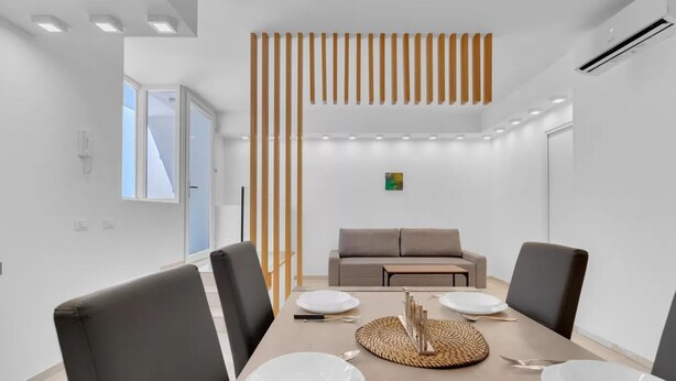 A modern dining room with a long table, chairs, and a decorative wooden panel. - MA6 [Cathedral] • Spacious luxury apartment in a central location • (Milano)