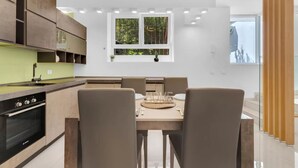 A modern kitchen with built-in appliances, a dining area with a wooden table and chairs, and a window with greenery visible outside. - MA6 [Cathedral] • Spacious luxury apartment in a central location • (Milano)