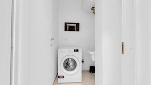 A compact laundry room with a front-loading washing machine, a small sink, and a toilet. - MA6 [Cathedral] • Spacious luxury apartment in a central location • (Milano)